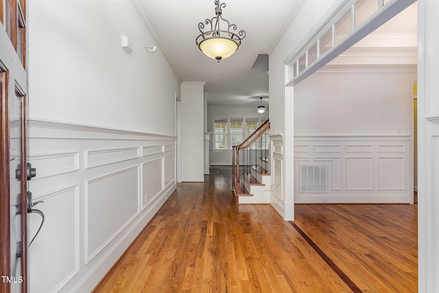 foyer with hardwood / wood-style floors, ornamental molding, and ceiling fan