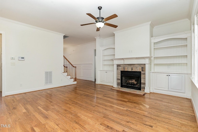 unfurnished living room with crown molding, ceiling fan, built in features, and light wood-type flooring