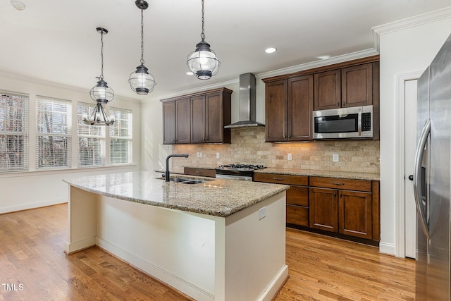 kitchen with appliances with stainless steel finishes, decorative light fixtures, sink, light stone counters, and wall chimney range hood