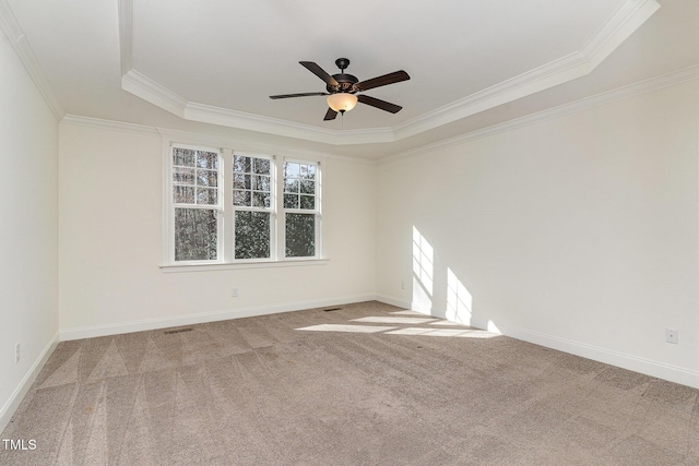 carpeted spare room with a raised ceiling, ornamental molding, and ceiling fan