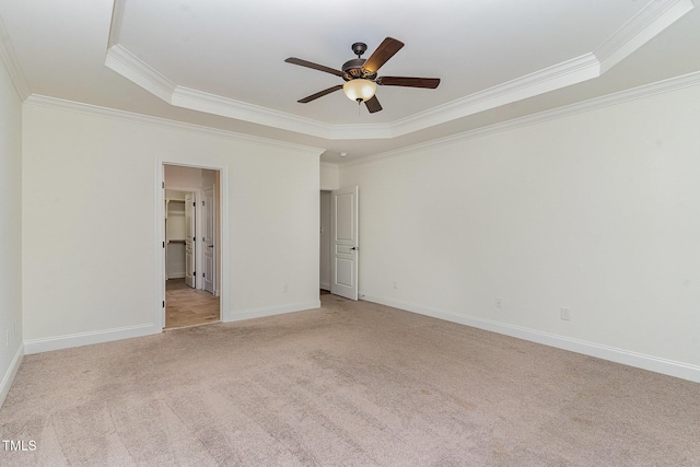 carpeted empty room featuring ceiling fan, ornamental molding, and a tray ceiling