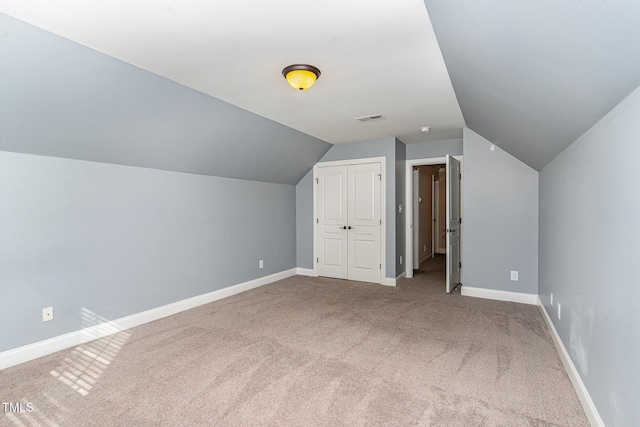 additional living space featuring vaulted ceiling and carpet flooring