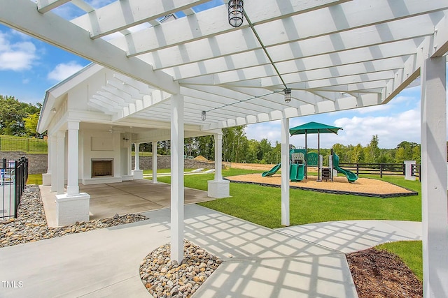 view of patio featuring a pergola, a playground, and exterior fireplace