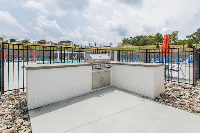 view of patio / terrace with a grill, a pool, and exterior kitchen