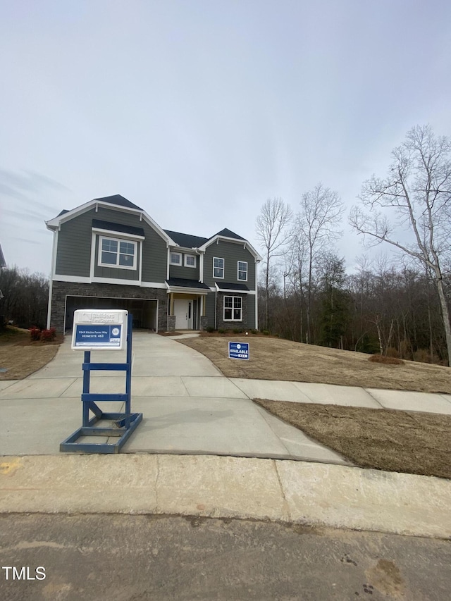 view of front of home with an attached garage, concrete driveway, and stone siding