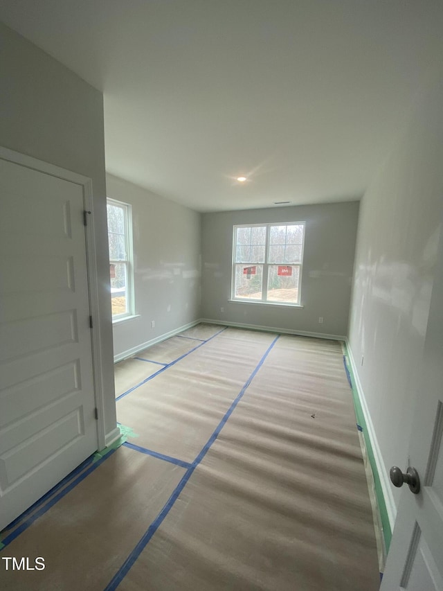 unfurnished room featuring a wealth of natural light, baseboards, and wood finished floors