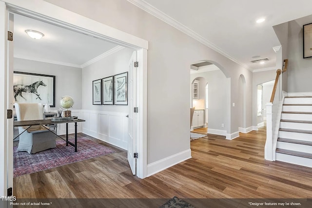 office area with visible vents, arched walkways, wood finished floors, and ornamental molding