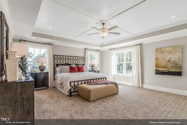 carpeted bedroom with a tray ceiling, multiple windows, crown molding, and baseboards