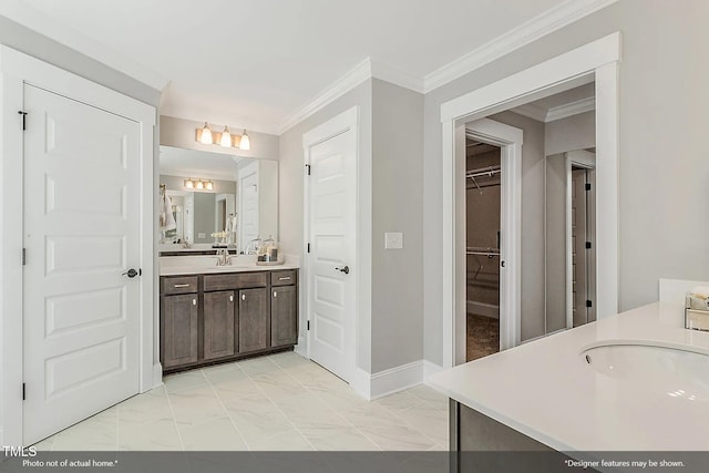 bathroom with marble finish floor, vanity, crown molding, baseboards, and a spacious closet