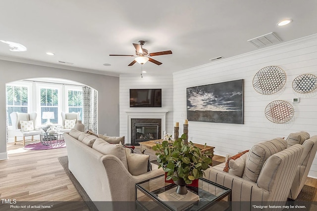 living area featuring visible vents, ceiling fan, ornamental molding, and light wood-style flooring