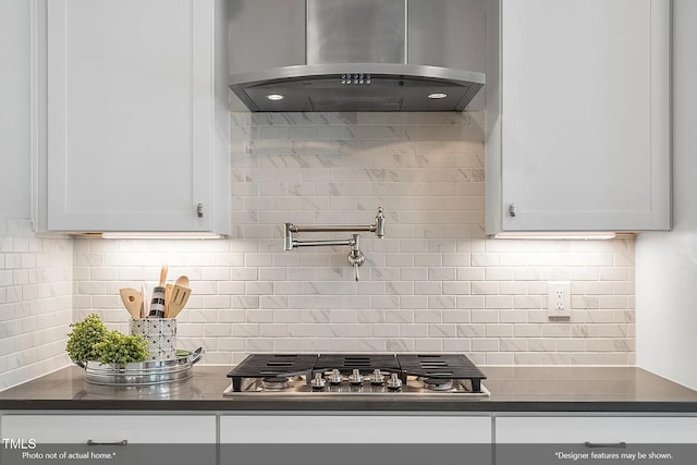 kitchen featuring dark countertops, extractor fan, stainless steel gas stovetop, and white cabinets