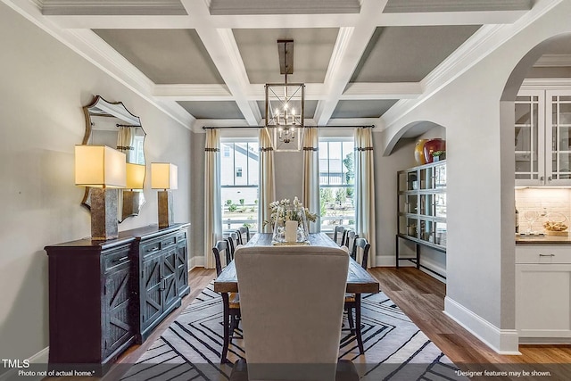 dining area with an inviting chandelier, wood finished floors, arched walkways, and baseboards