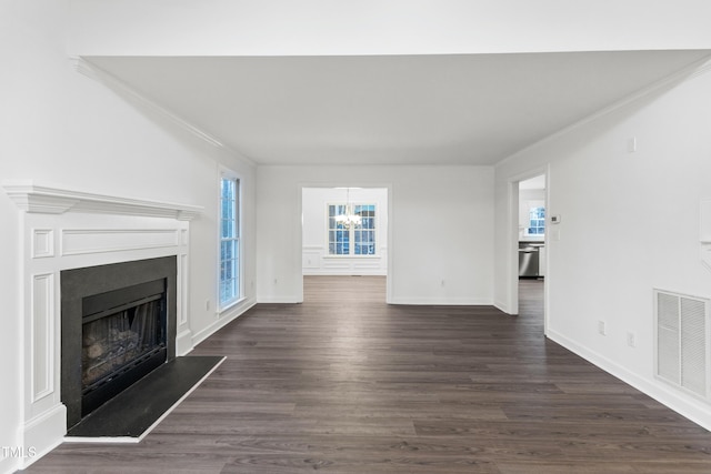 unfurnished living room featuring dark hardwood / wood-style flooring, an inviting chandelier, and ornamental molding