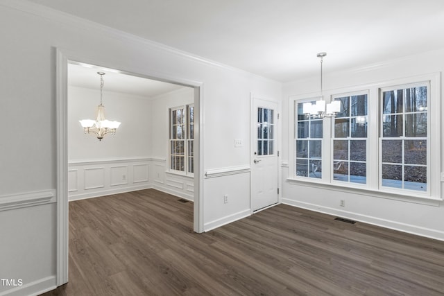 unfurnished dining area featuring dark hardwood / wood-style floors, ornamental molding, and an inviting chandelier