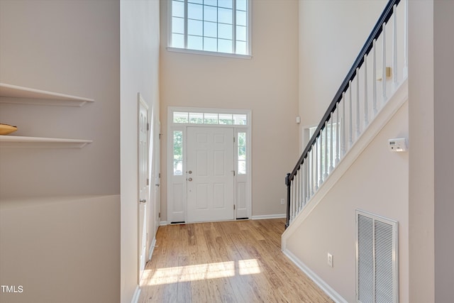 foyer with a high ceiling and light hardwood / wood-style floors