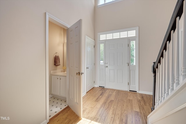 foyer entrance featuring plenty of natural light, light wood-type flooring, and a towering ceiling