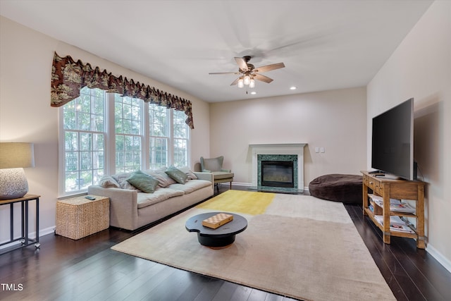 living room featuring dark hardwood / wood-style floors, ceiling fan, and a premium fireplace