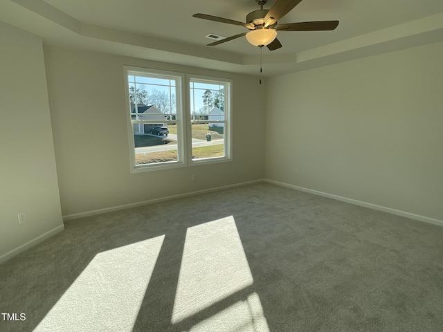 empty room featuring carpet floors, a tray ceiling, and ceiling fan