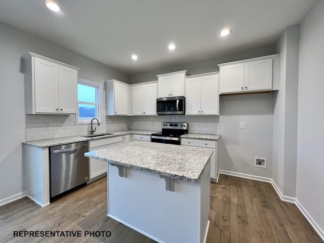 kitchen with a sink, a kitchen island, white cabinetry, and stainless steel appliances