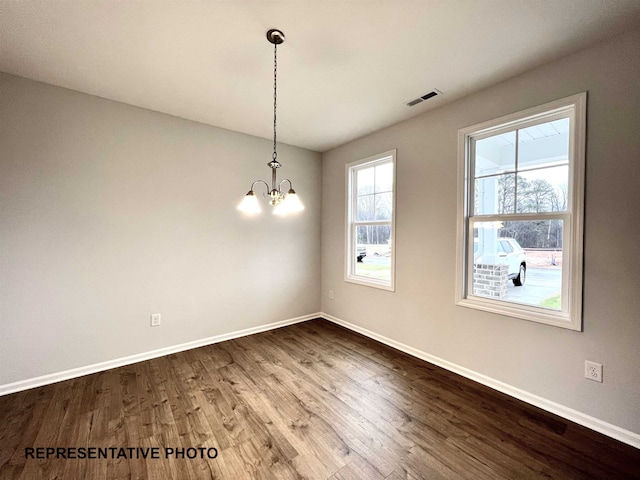 unfurnished dining area with visible vents, baseboards, a chandelier, and dark wood-style flooring