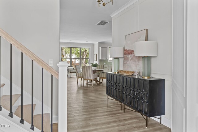 entryway featuring wood finished floors, visible vents, crown molding, and stairs