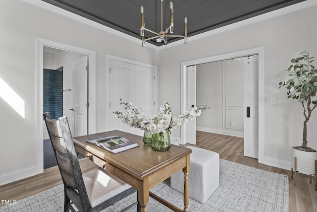 home office featuring a chandelier, baseboards, and wood finished floors