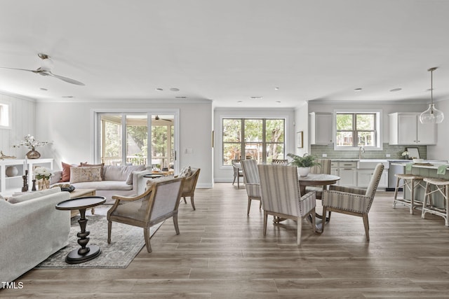 living room featuring baseboards, a ceiling fan, ornamental molding, wood finished floors, and recessed lighting