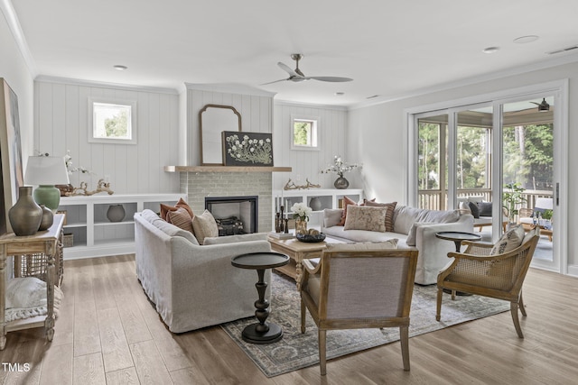 living room featuring a fireplace, ornamental molding, a wealth of natural light, and wood finished floors