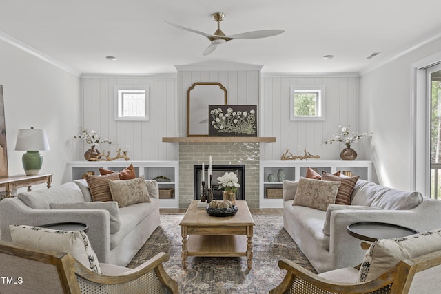 living room featuring a healthy amount of sunlight, a brick fireplace, visible vents, and crown molding