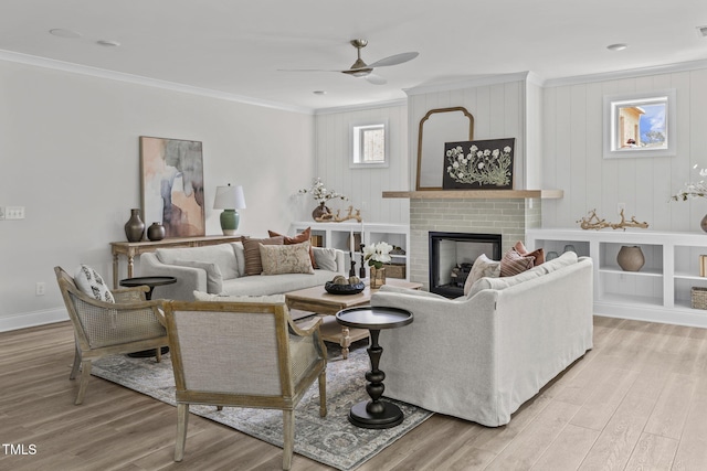 living room featuring light wood-type flooring, a fireplace, and crown molding