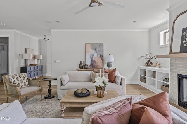 living area featuring crown molding, a ceiling fan, a brick fireplace, wood finished floors, and baseboards