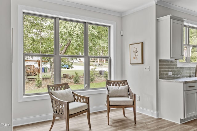 sitting room with light wood-style flooring, ornamental molding, and baseboards