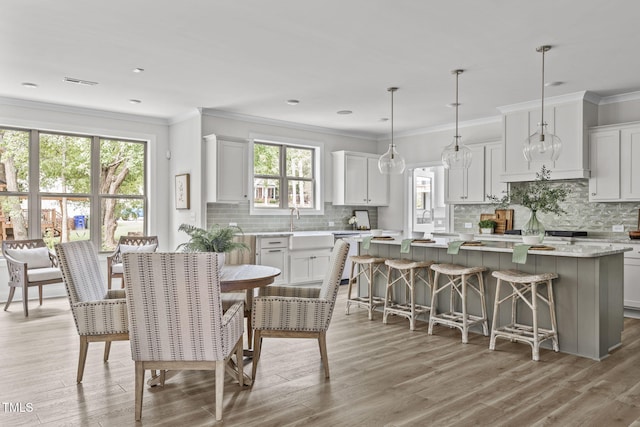 dining area with visible vents, ornamental molding, and light wood-style flooring