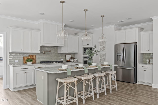 kitchen featuring appliances with stainless steel finishes, white cabinets, ornamental molding, and light wood finished floors