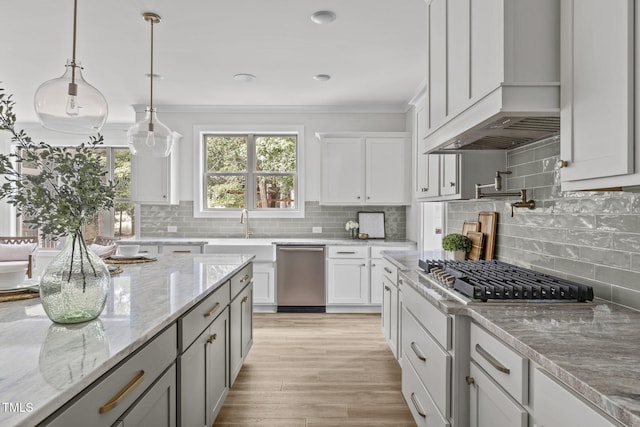 kitchen with light stone countertops, stainless steel appliances, white cabinets, ornamental molding, and decorative backsplash