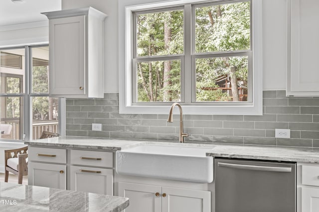 kitchen with a sink, a healthy amount of sunlight, backsplash, and dishwasher