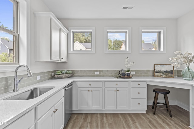 kitchen featuring visible vents, stainless steel dishwasher, light wood-style floors, white cabinets, and a sink