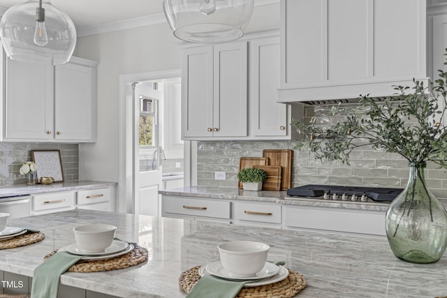 kitchen featuring light stone counters, white cabinets, appliances with stainless steel finishes, backsplash, and crown molding