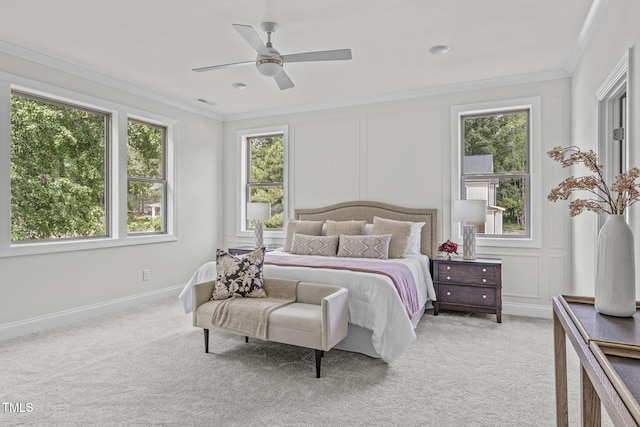 bedroom featuring ceiling fan, ornamental molding, light colored carpet, and a decorative wall