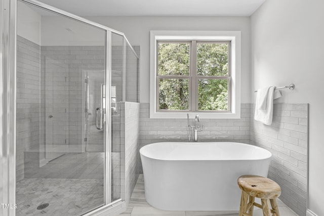 bathroom featuring a freestanding tub, a shower stall, and tile walls