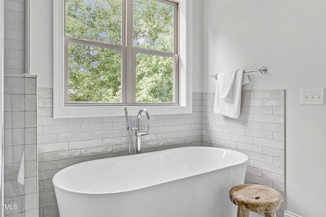 full bath with a freestanding tub and tile walls