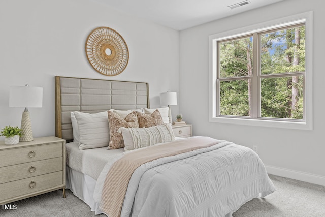 bedroom with baseboards, visible vents, and light colored carpet