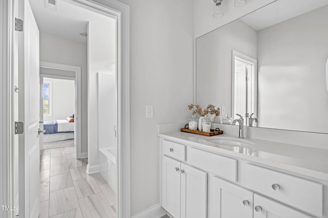 bathroom featuring visible vents, connected bathroom, vanity, and baseboards