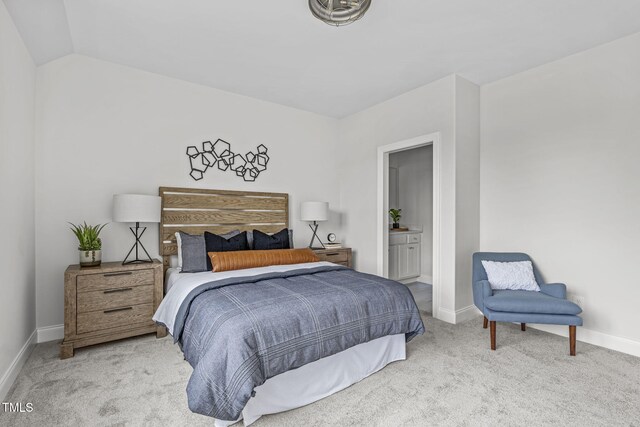 carpeted bedroom with vaulted ceiling, baseboards, and ensuite bathroom