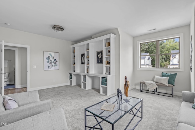 carpeted living room with visible vents, baseboards, and built in study area