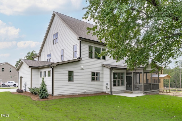 back of property featuring a sunroom, a patio, a lawn, and roof with shingles