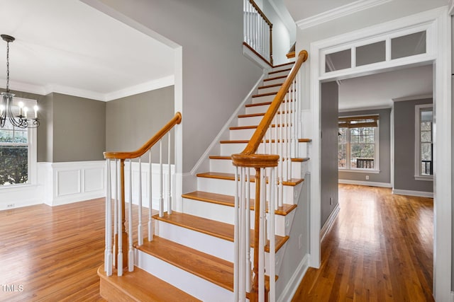 stairs featuring hardwood / wood-style floors, a chandelier, and ornamental molding