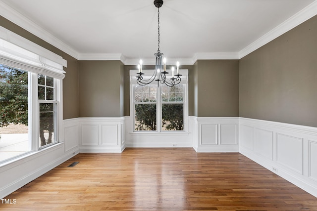 unfurnished dining area with an inviting chandelier, light hardwood / wood-style floors, and crown molding