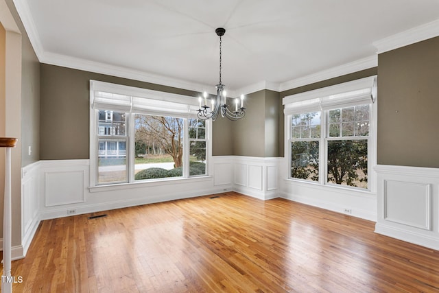 unfurnished dining area featuring light hardwood / wood-style flooring, a chandelier, and crown molding