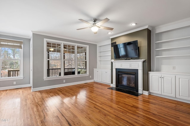 unfurnished living room with crown molding, built in features, light wood-type flooring, and ceiling fan